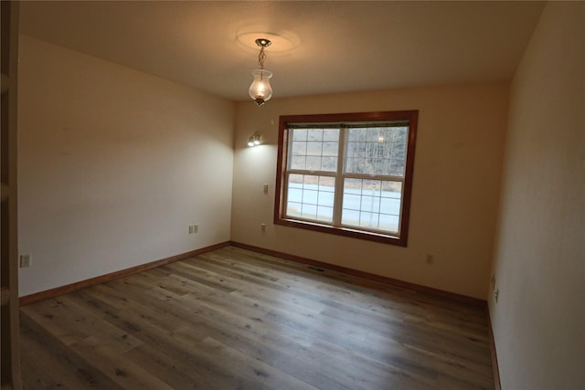 spare room with visible vents, wood finished floors, and baseboards