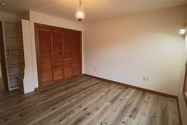 unfurnished bedroom featuring a closet, baseboards, and wood finished floors