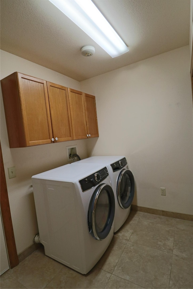 laundry area with baseboards, cabinet space, a textured ceiling, and washing machine and dryer