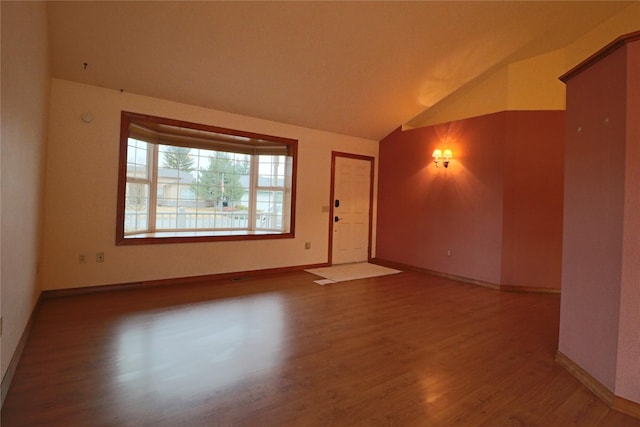 unfurnished room with wood finished floors, baseboards, and vaulted ceiling