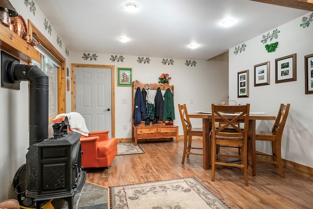 dining space featuring light wood-type flooring, baseboards, and a wood stove
