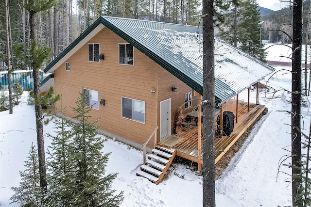 snow covered rear of property featuring metal roof