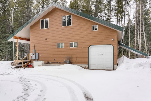 snow covered property with a garage