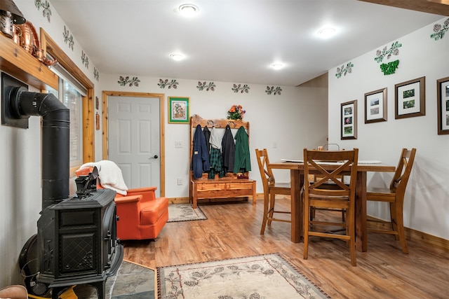 dining room featuring light wood-style flooring, a wood stove, and baseboards