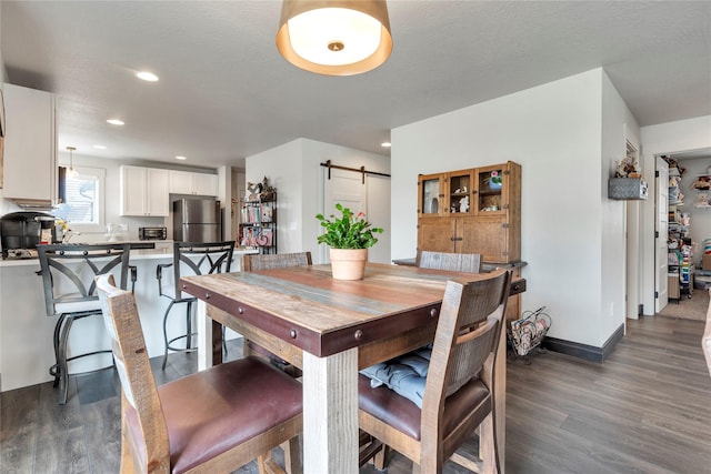 dining space with dark wood-type flooring, baseboards, a barn door, recessed lighting, and a textured ceiling