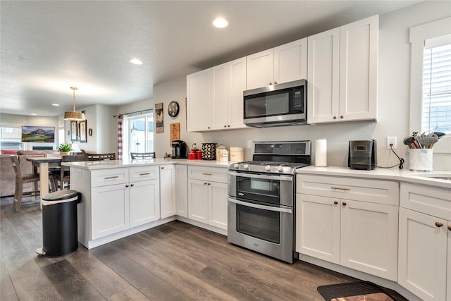 kitchen featuring dark wood finished floors, white cabinetry, appliances with stainless steel finishes, a peninsula, and light countertops