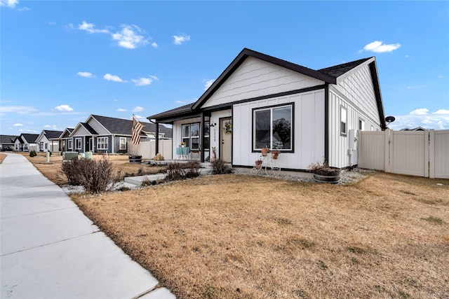 view of front of house with a gate, fence, a residential view, board and batten siding, and a front yard