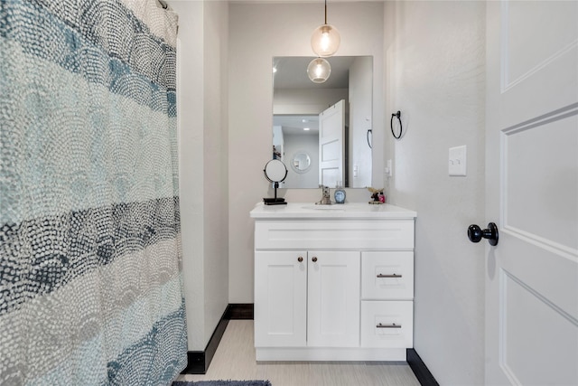 bathroom featuring vanity, curtained shower, and baseboards