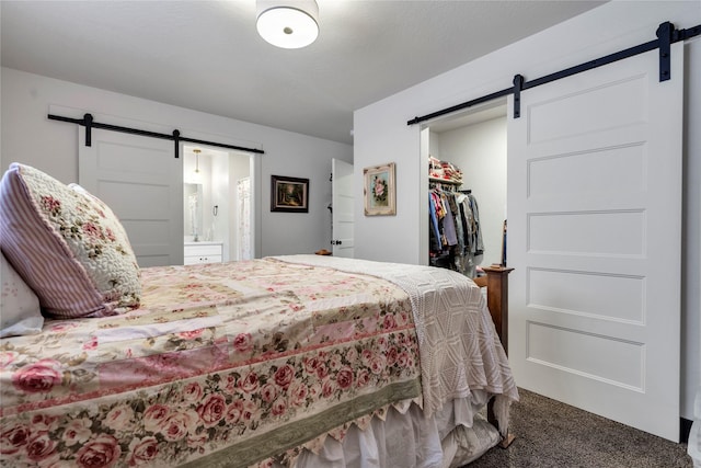 bedroom with a closet, carpet flooring, a walk in closet, and a barn door