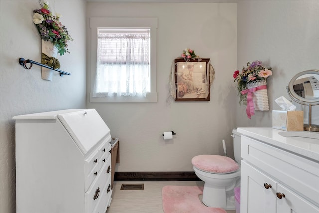 bathroom with vanity, toilet, baseboards, and visible vents