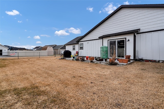 exterior space featuring a lawn, board and batten siding, and fence