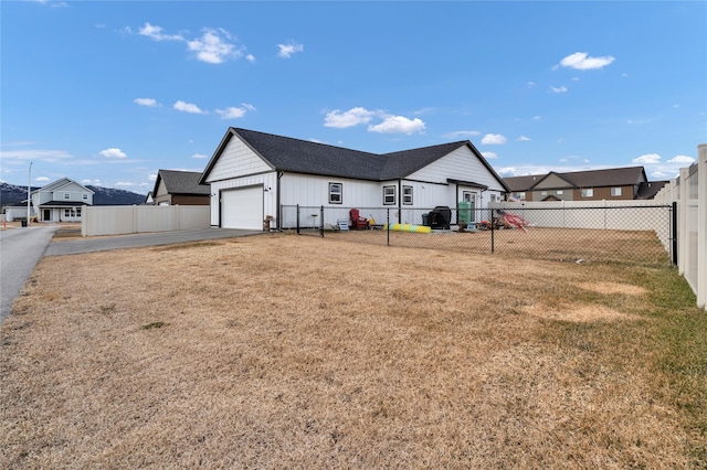 back of property featuring a garage, a yard, fence private yard, and driveway