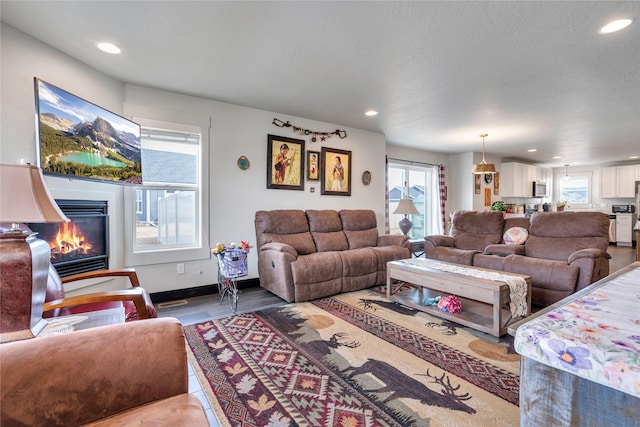 living area with a glass covered fireplace, recessed lighting, and a healthy amount of sunlight