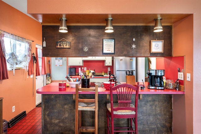 kitchen with a kitchen breakfast bar, white cabinets, dark floors, and freestanding refrigerator