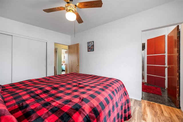 bedroom with a ceiling fan, wood finished floors, and a closet