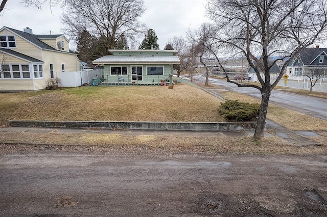 view of front of property featuring a porch, metal roof, a front yard, and fence