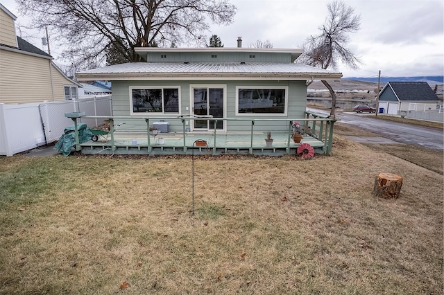 back of property with metal roof, a yard, and fence