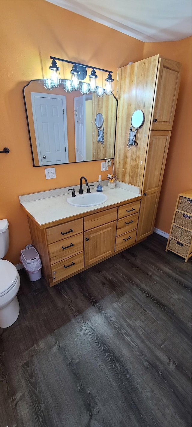 bathroom featuring baseboards, toilet, wood finished floors, and vanity