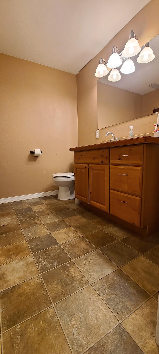 bathroom with baseboards, toilet, and vanity