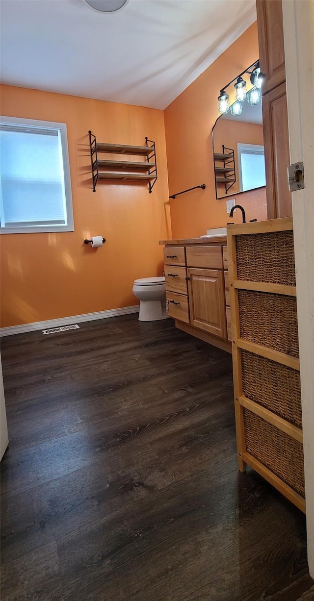 bathroom with a healthy amount of sunlight, toilet, vanity, and wood finished floors