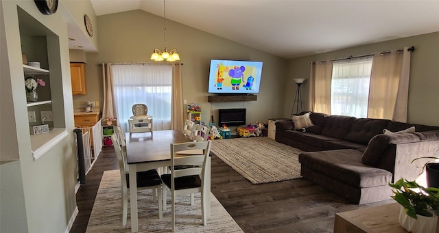 living room with dark wood finished floors, lofted ceiling, a notable chandelier, and a lit fireplace