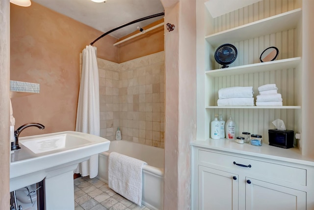 bathroom with shower / bath combo with shower curtain and a sink