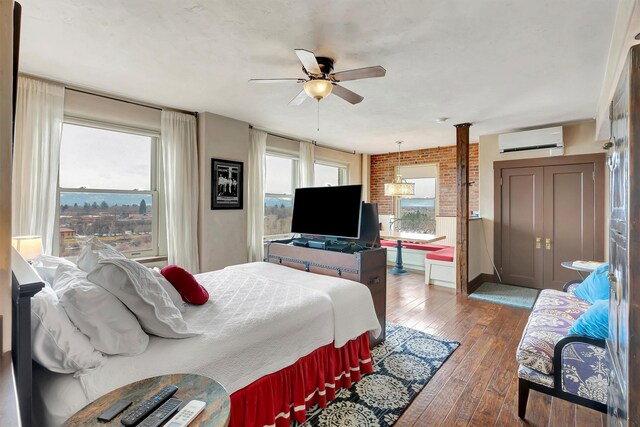 131 S Higgins Ave Unit 7-2, Missoula, MT 59802 - bedroom featuring a wall unit AC, hardwood / wood-style floors, brick wall, and ceiling fan
