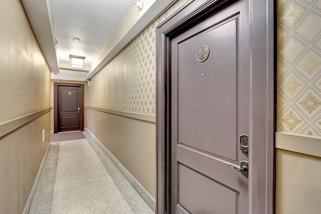 hallway featuring baseboards and wallpapered walls