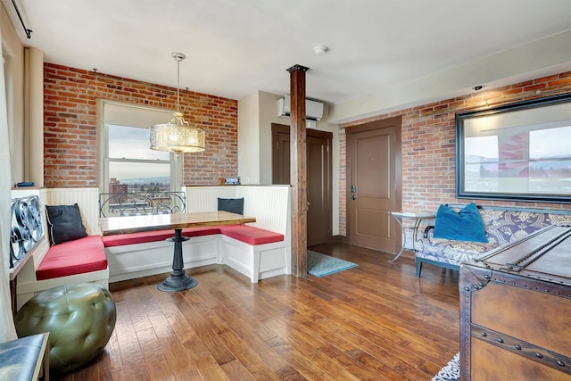 interior space with hardwood / wood-style floors, a wall mounted air conditioner, brick wall, and wainscoting