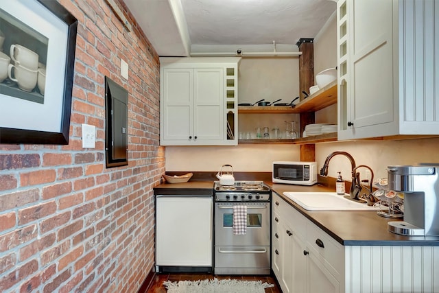 kitchen featuring white microwave, brick wall, stainless steel range with gas cooktop, open shelves, and a sink