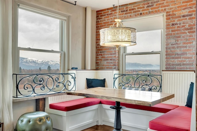 dining space featuring a wainscoted wall, brick wall, and breakfast area