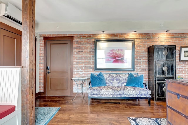 sitting room with wood finished floors and brick wall