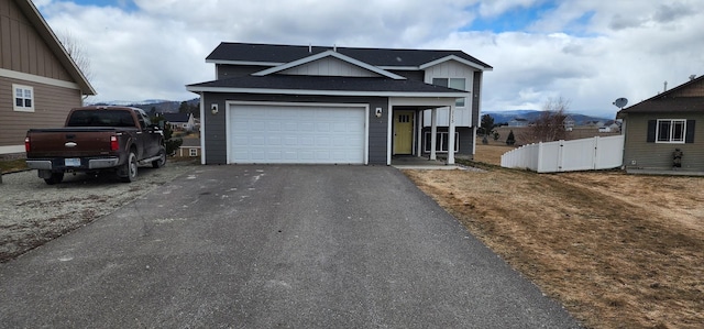 view of front facade featuring fence, aphalt driveway, roof with shingles, an attached garage, and a gate