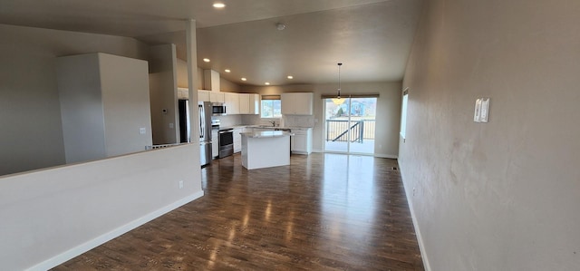 kitchen with lofted ceiling, decorative backsplash, stainless steel appliances, white cabinetry, and dark wood-style flooring