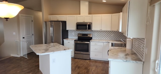 kitchen with a sink, white cabinetry, stainless steel appliances, and vaulted ceiling