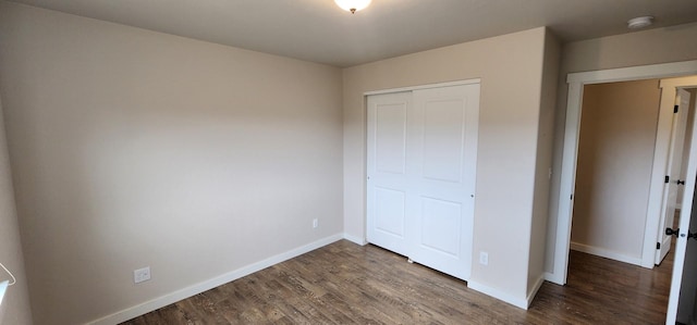 unfurnished bedroom with wood finished floors, a closet, and baseboards