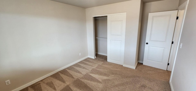 unfurnished bedroom featuring light colored carpet, baseboards, and a closet