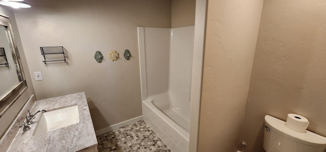 full bathroom with toilet, vanity, baseboards, and a textured wall