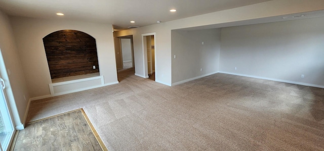 carpeted spare room featuring arched walkways, visible vents, recessed lighting, and baseboards