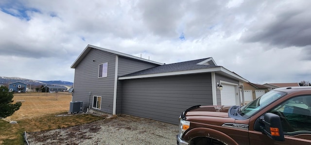 view of home's exterior featuring a garage, central air condition unit, and a mountain view