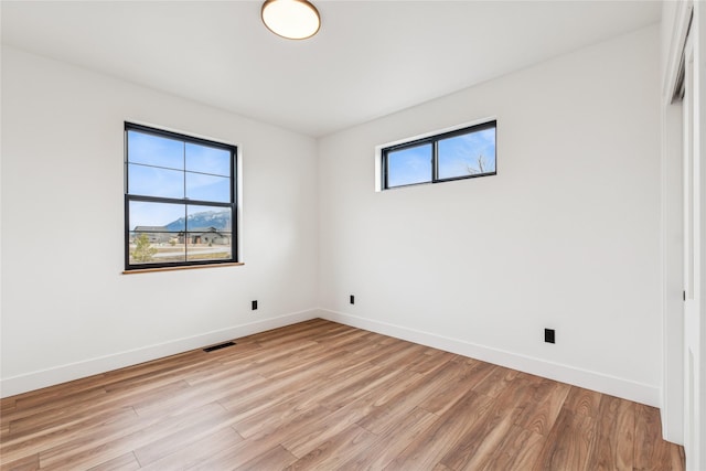 spare room with a wealth of natural light, visible vents, light wood-type flooring, and baseboards