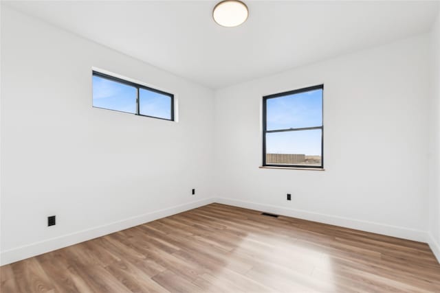 spare room with visible vents, light wood-style flooring, and baseboards