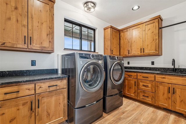 laundry room featuring washing machine and dryer, recessed lighting, light wood-style floors, cabinet space, and a sink