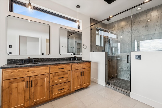 bathroom featuring tile patterned flooring, double vanity, a marble finish shower, and a sink