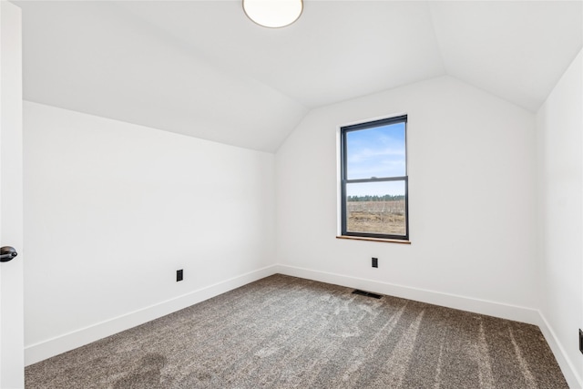 additional living space featuring dark colored carpet, baseboards, and vaulted ceiling