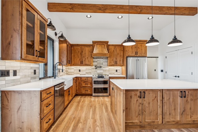 kitchen featuring custom range hood, beam ceiling, light wood-style floors, stainless steel appliances, and a sink