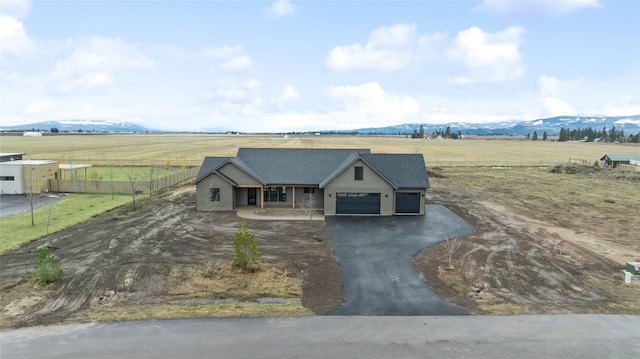 view of front of home with aphalt driveway, fence, a mountain view, a rural view, and an attached garage