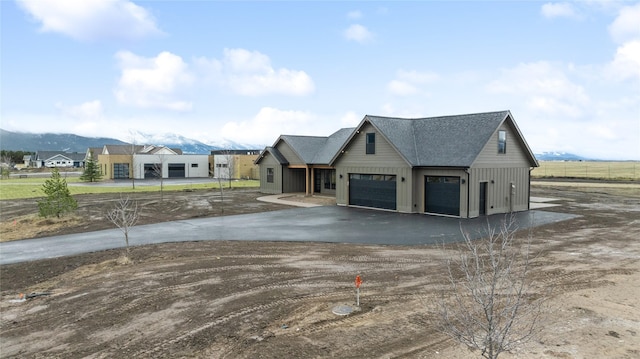 exterior space with a mountain view, driveway, an attached garage, and roof with shingles