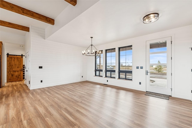 unfurnished dining area with light wood finished floors, baseboards, a chandelier, beamed ceiling, and a barn door