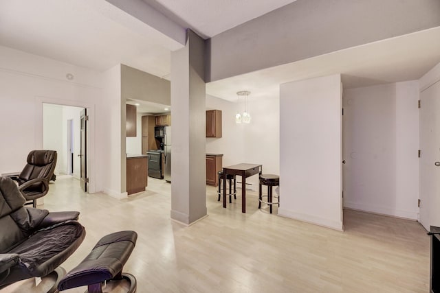 living room featuring vaulted ceiling, a notable chandelier, baseboards, and light wood-type flooring